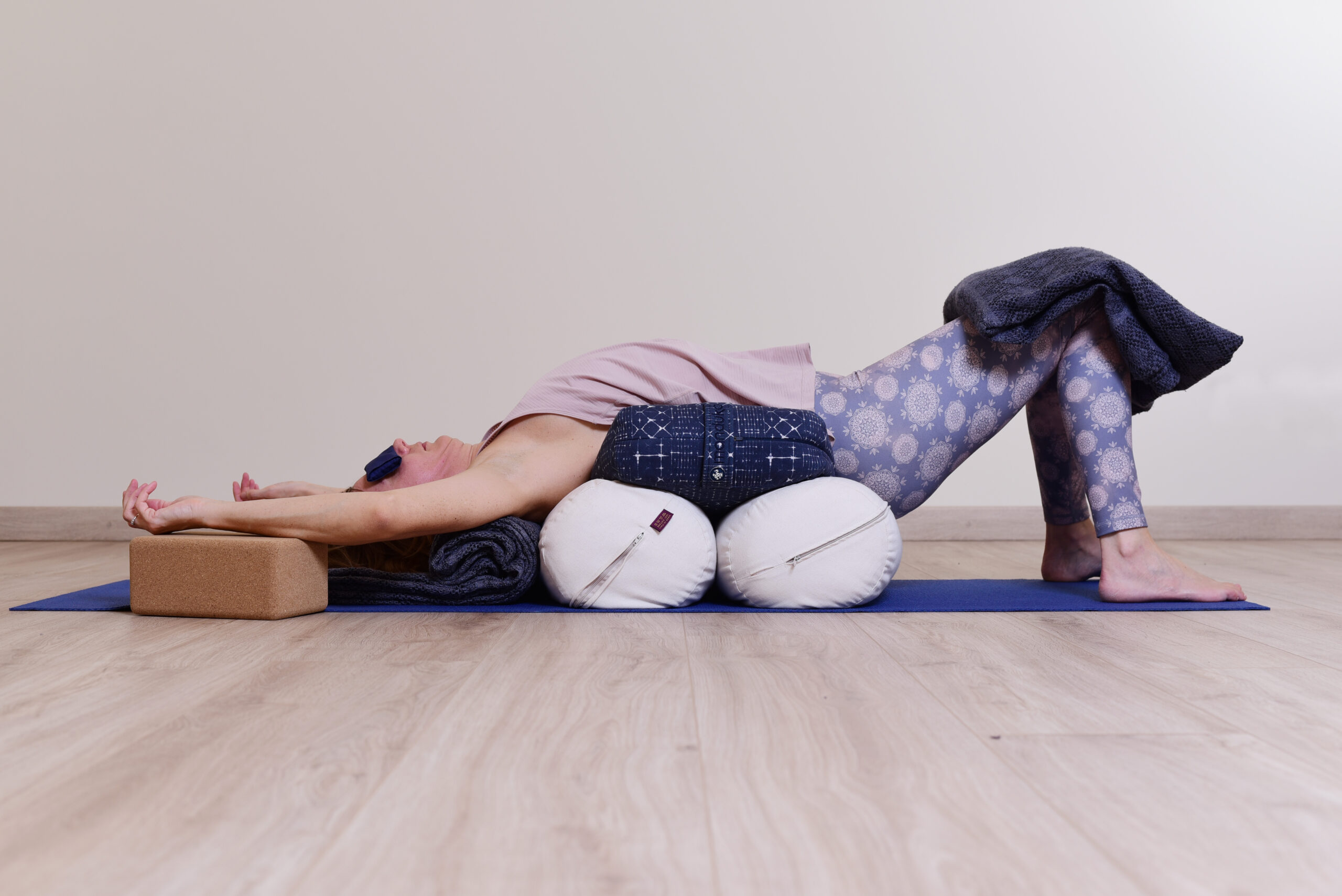 Audrey Favreau dans une posture de Yoga Restauratif soutenue par deux bolsters, les bras relâchés au-dessus de la tête