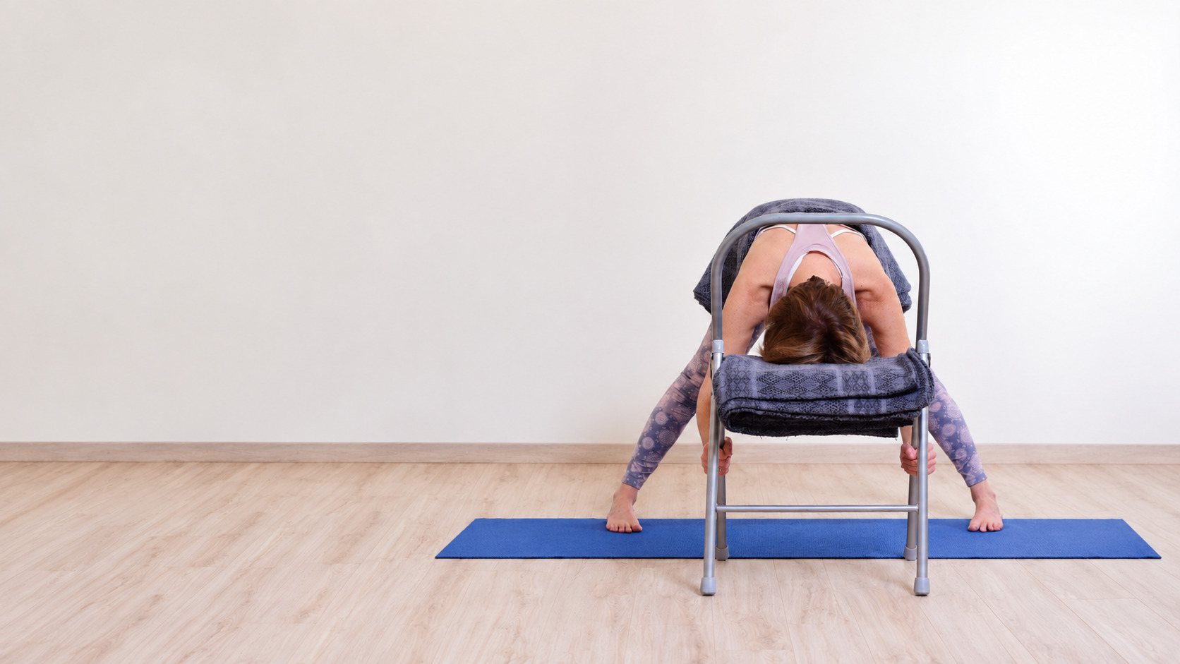 Audrey Favreau dans une flexion avant soutenue avec une chaise pendant une pratique de Yoga Restauratif